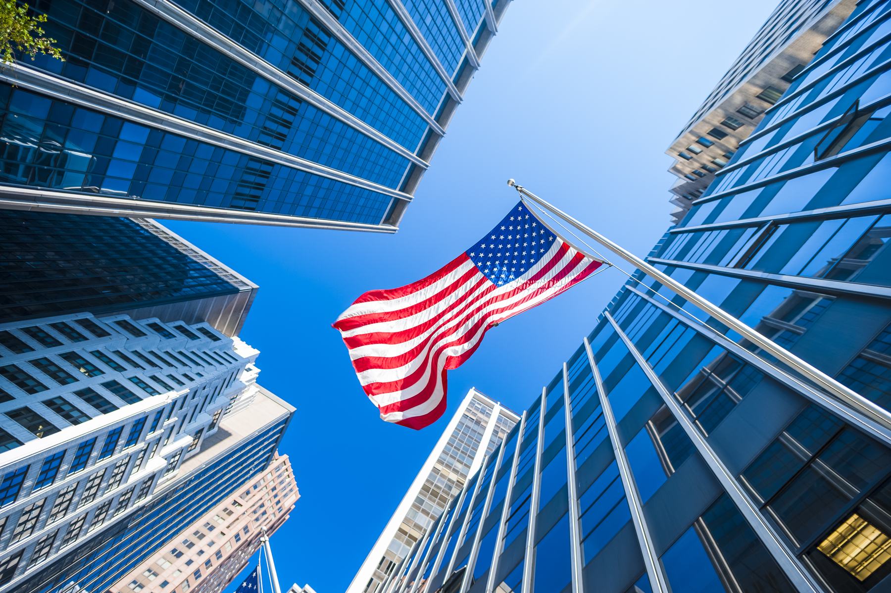 An American flag flying between glass office towers
