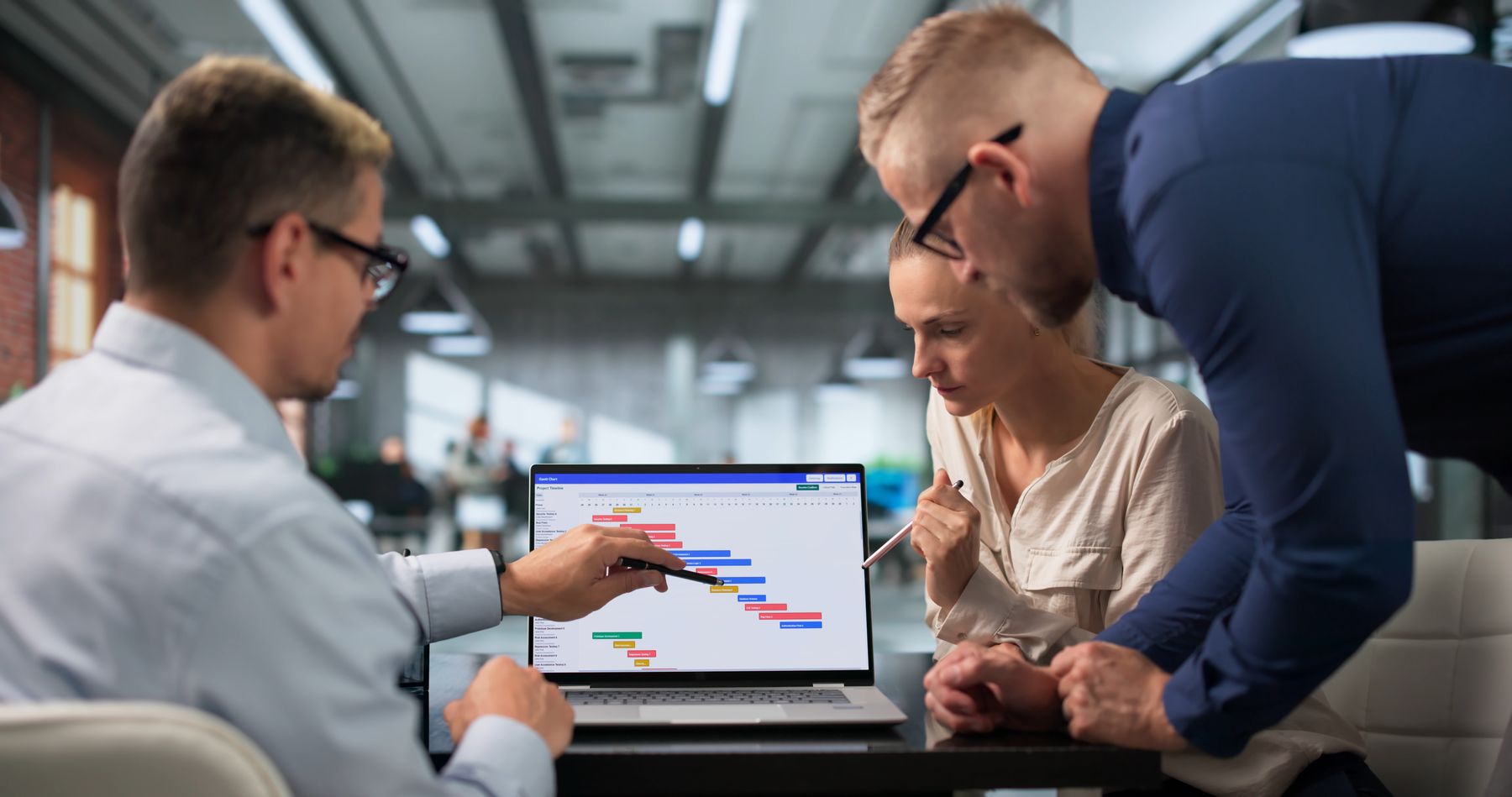 A project team reviewing a bid schedule on a laptop