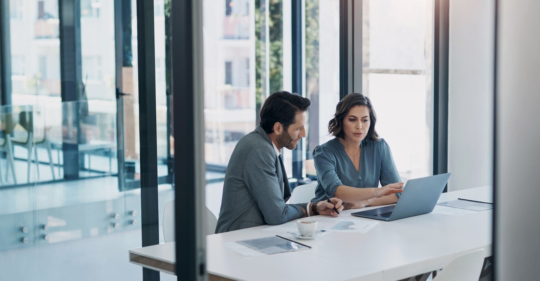 Two consultants reviewing an agreement together at a laptop