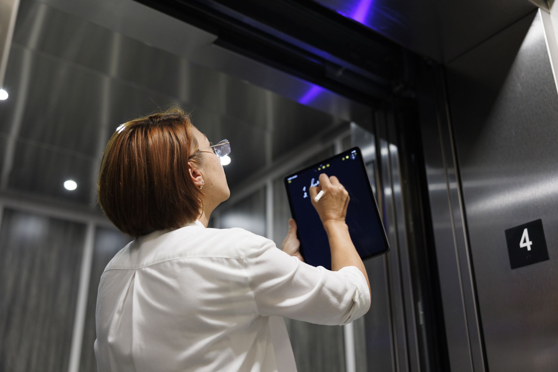An inspector with a tablet checking an elevator car